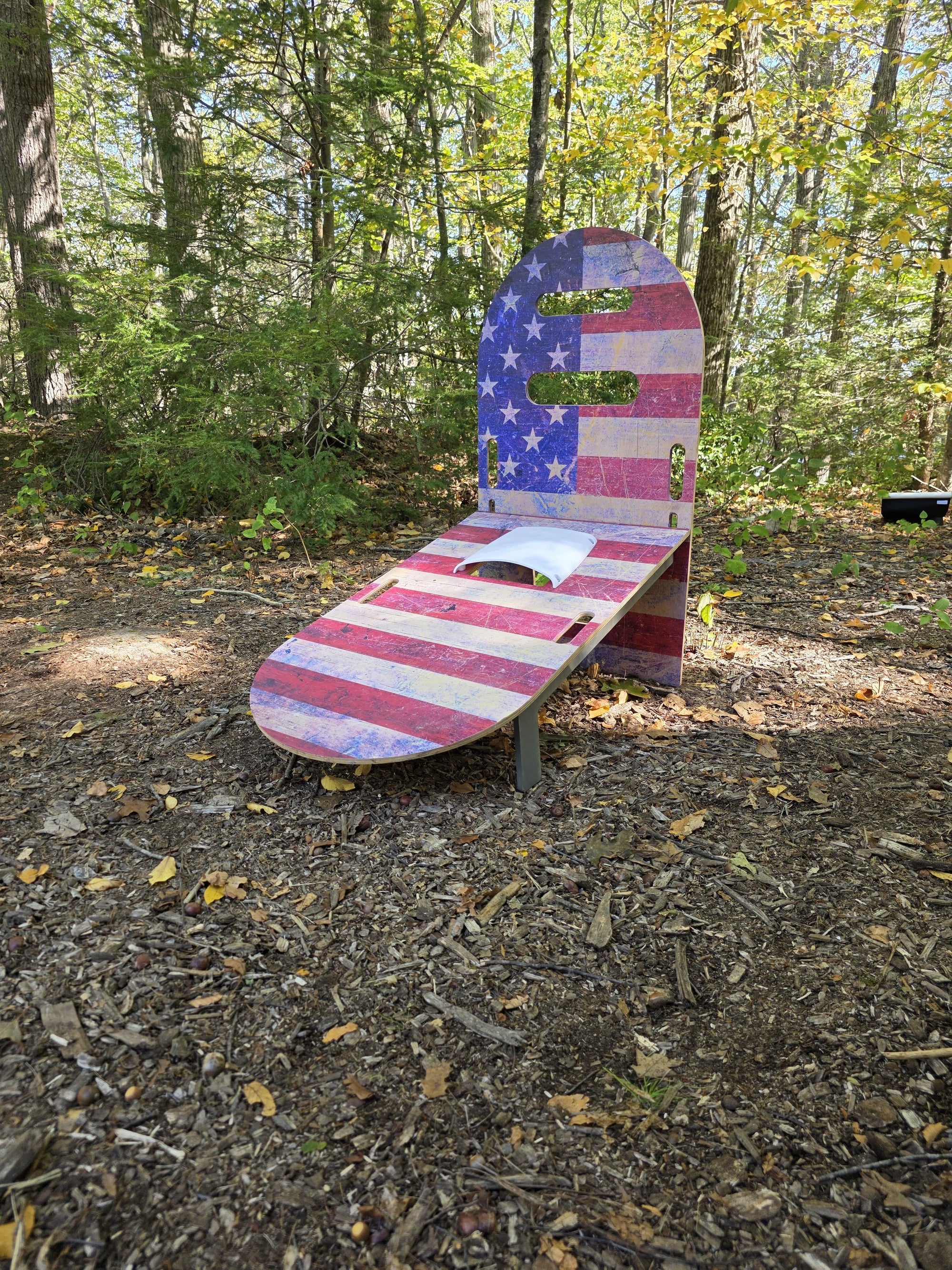 Angled view of SlotShot American flag board outdoors surrounded by trees